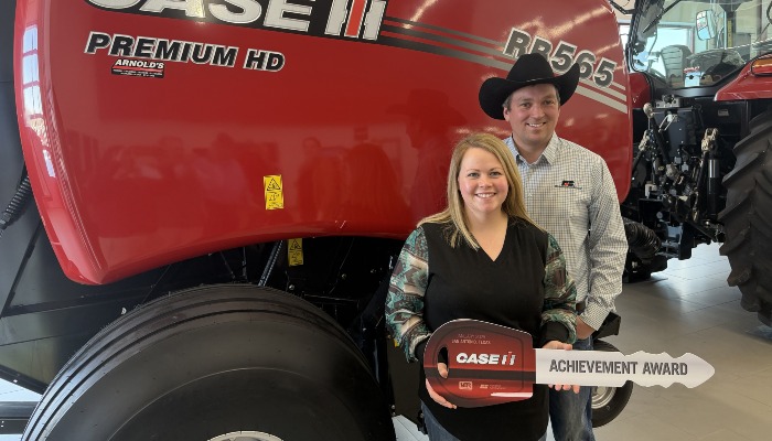 two people standing in front of round baler